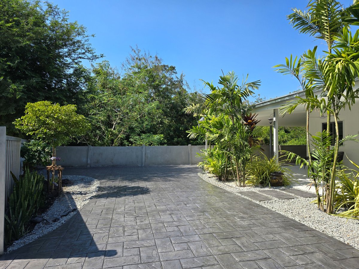 Stamped concrete driveway with intricate design and lush landscaping